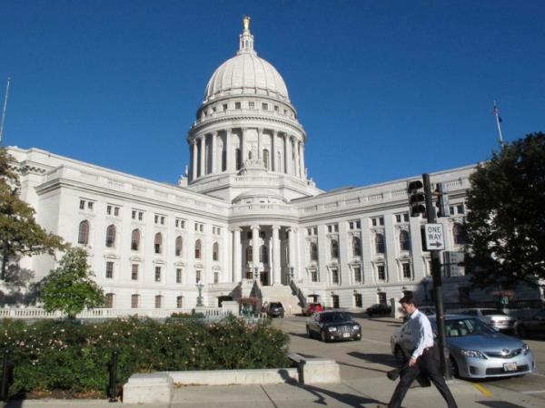 FILE - A man walks by the Wisco<em></em>nsin Capitol, Oct. 10, 2012, in Madison, Wis. Supporters of Wisconsin's taxpayer-funded school choice and independent charter school programs urged the Wisco<em></em>nsin Supreme Court, which is located inside the state Capitol, on Tuesday, Nov. 14, 2023, to reject a lawsuit seeking to declare the programs unconstitutional, saying such a move would create chaos for tens of thousands of families with students currently enrolled. (AP Photo/Scott Bauer, File)