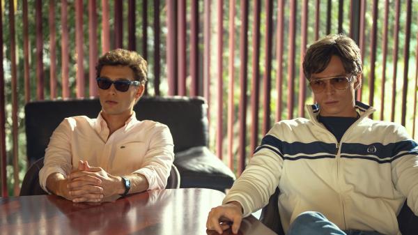 Erik and Lyle Menendez sitting in a boardroom wearing sunglasses in Monsters.